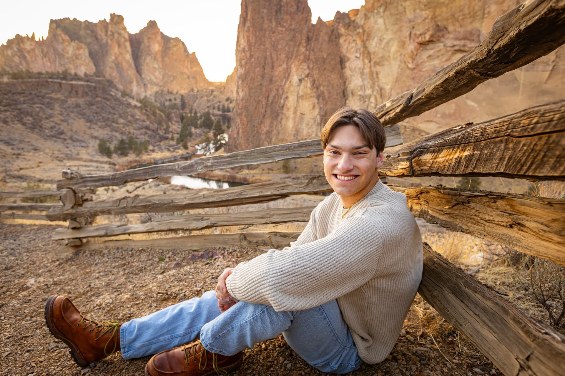 Senior leaning against a split rail fence in the high desert