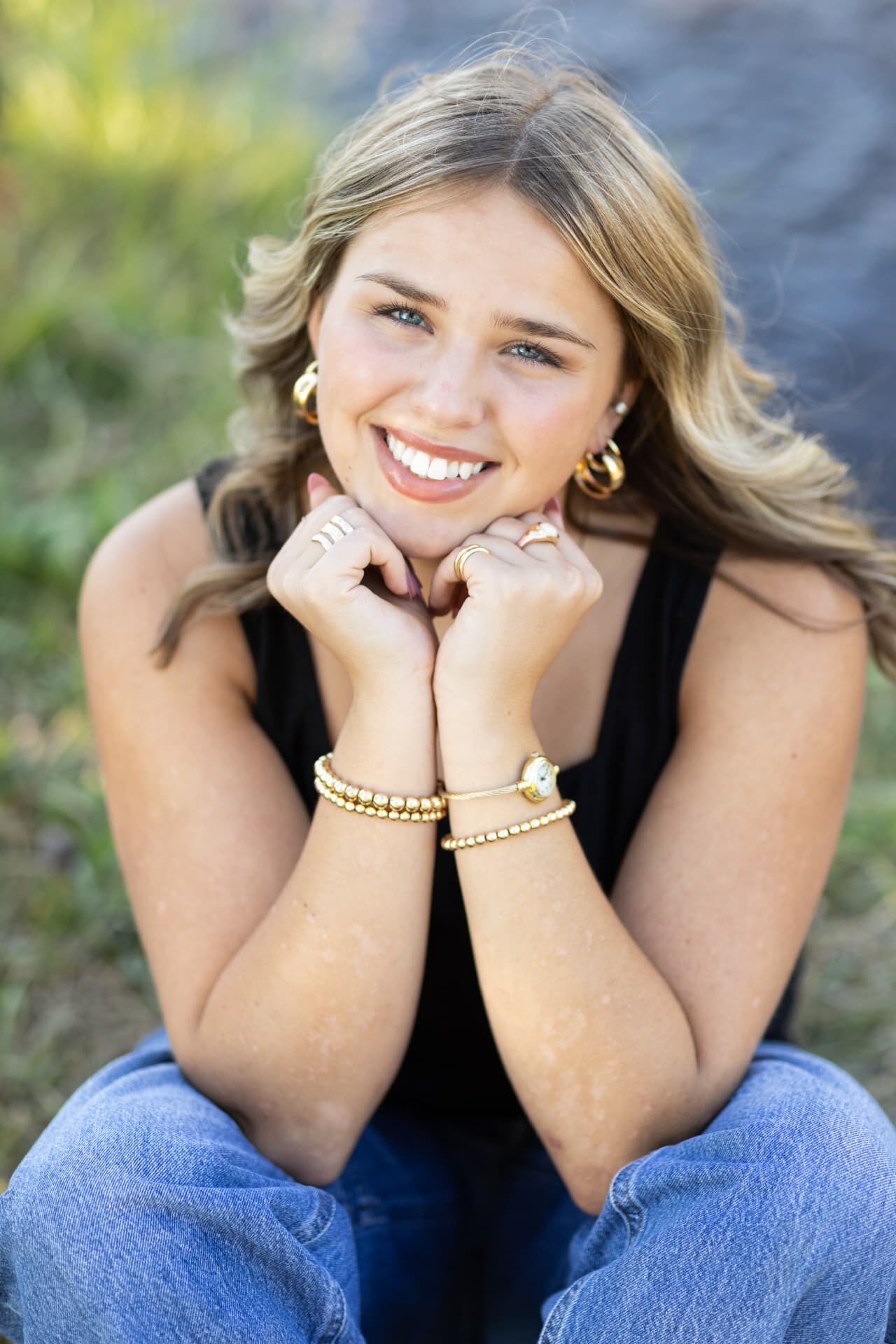 Close up senior portrait of a smiling girl resting her chin on her hands