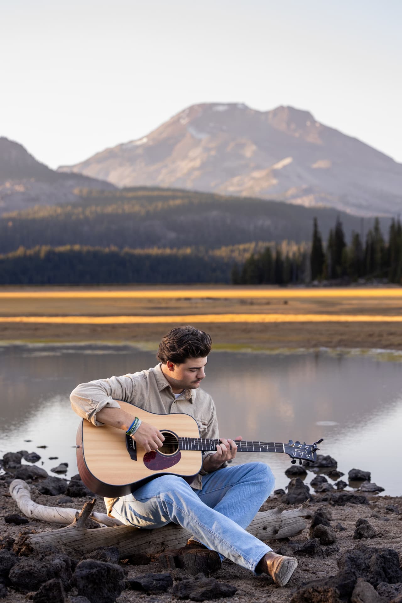 Senior guy playing guitar beside a mountain lake in Central Oregon