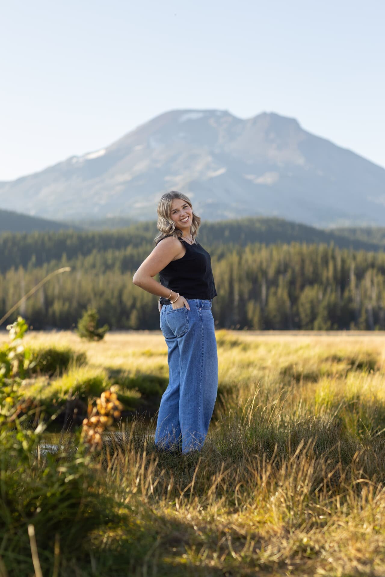 Senior girl standing in a meadow below South Sister near Sparks Lake