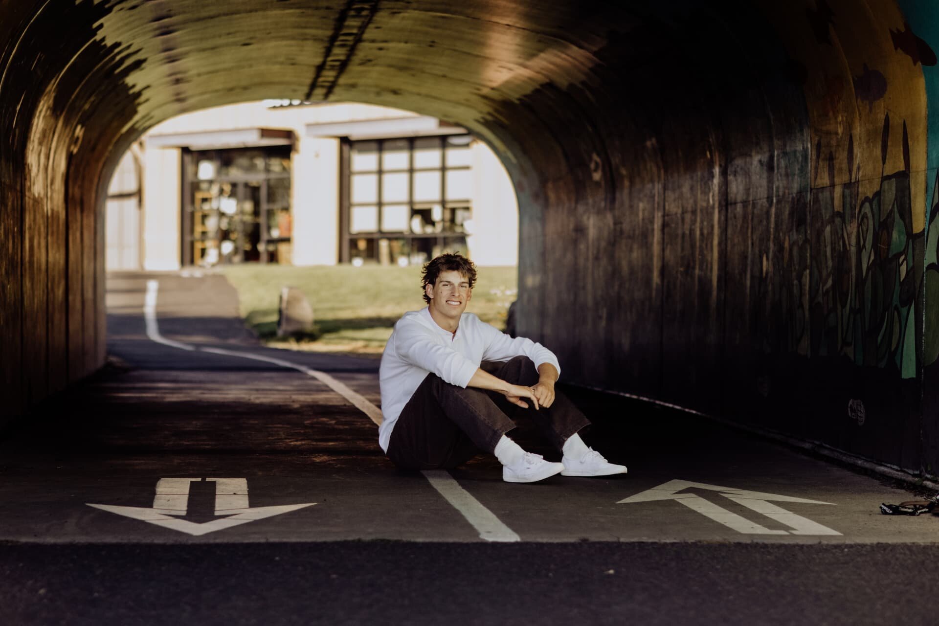 Senior guy smiling while sitting in a warm-lit pedestrian tunnel