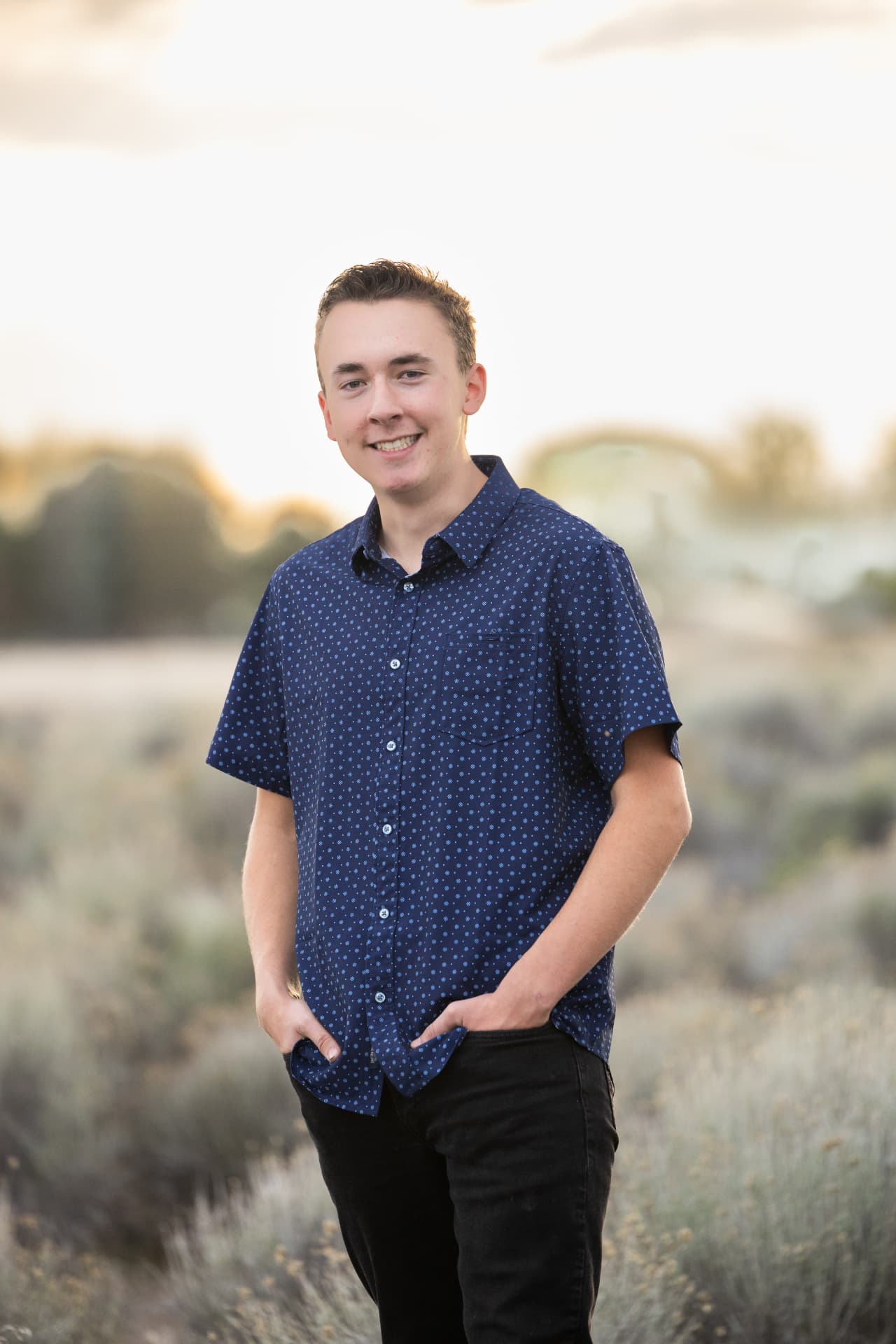 Senior guy standing in a field at sunset with soft golden light
