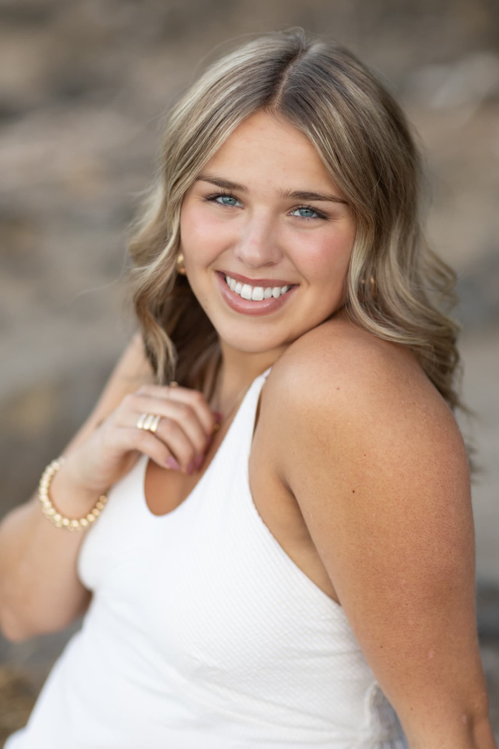 Close up senior portrait of a smiling girl in a white top