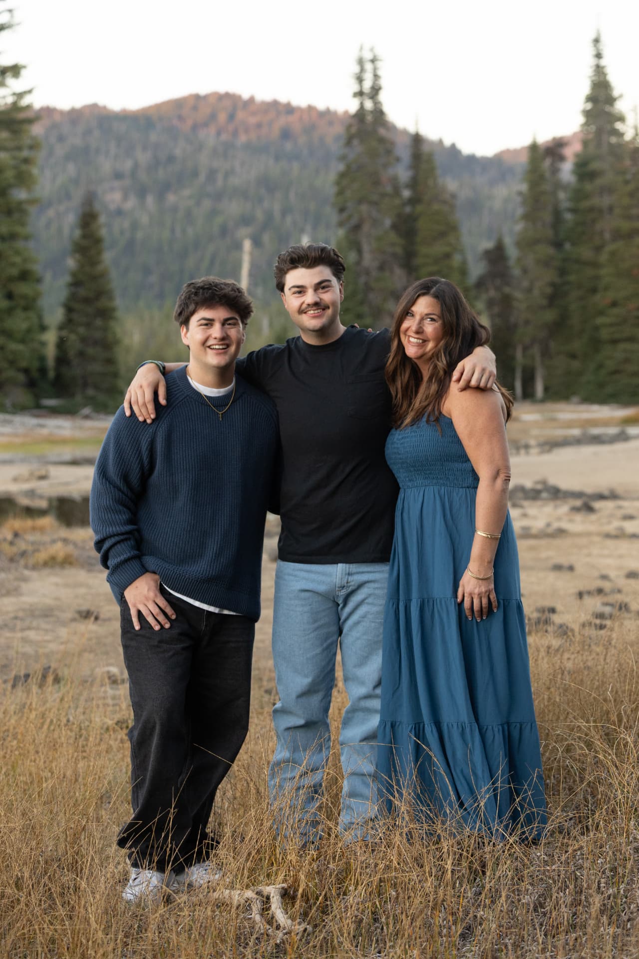 Mother with her two sons standing together in golden grass below the Cascades